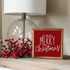 Merry Christmas sign with a cranberry red background and white font.